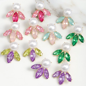 Macro detail of luxury teardrop pearl earrings with colorful marquise crystals on marble