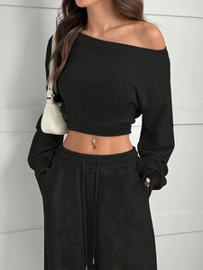 Detail eines schwarzen schulterfreien Crop-Tops und Jogginghose mit weicher Strickstruktur