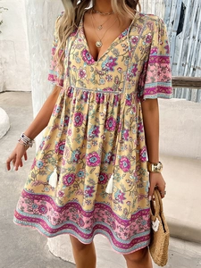 Detail of bohemian V-neck floral dress with tassel ties and vibrant yellow print