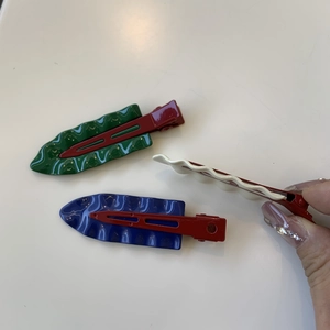 Close-up of three colorful wave-pattern hair clips with vintage red metal bases