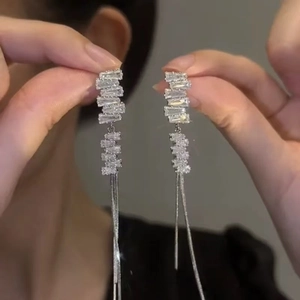 Detailed view of silver dangle earrings with baguette-cut rhinestones and tassel chains