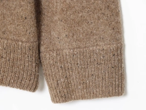 Dettaglio dei polsini a costine di un maglione in maglia tweed marrone strutturato