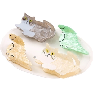 Set of four cute acetate dinosaur and cat hair claws with marble texture on ceramic plate