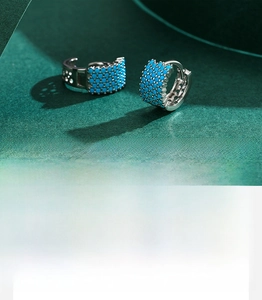 Macro shot of silver sterling earrings featuring inlaid bright blue turquoise stones