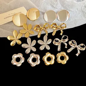 Boucles d'oreilles chic nœud et fleur en métal doré et argenté sur fond noir élégant