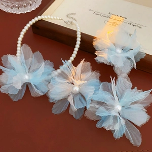 Detail of mesh flower necklace with pearls and floral brooch on wooden frame