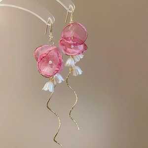 Detail of pink fabric flower earrings with white lily pendants and golden wavy tassels