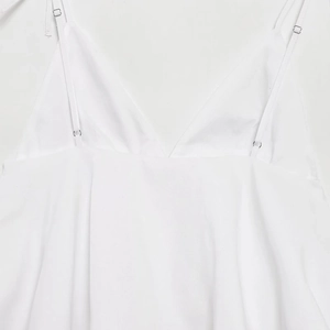 Detail of adjustable shoulder straps and V-neckline on white sleeveless crop top