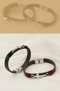 Gros plan du pendentif croix en acier inoxydable et bracelet en cuir tressé avec fermoir