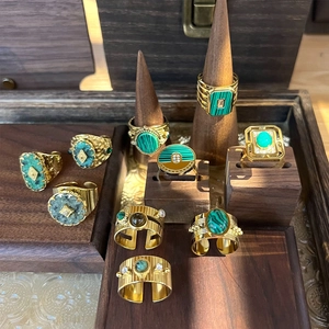 Goldene Vintage-Boho-Ringe mit grünen Natursteinen auf hölzernen Schmuckständern präsentiert