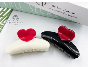 Detail of 8.3cm hair claw clips in cream and black featuring glossy red 3D heart motifs