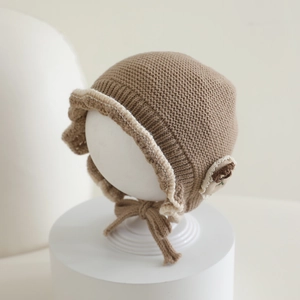 Detail of baby knit hat showing soft brown yarn texture and cream ruffled edges