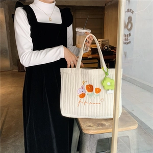 Close-up of white quilted tote bag with tulip embroidery and green flower charm