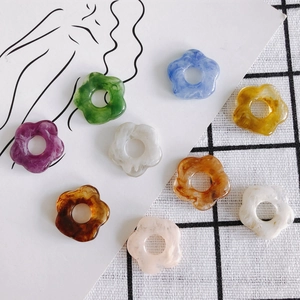 Flat lay of colorful 26mm resin flower charms in purple, green, blue and tortoiseshell