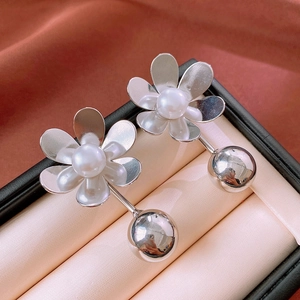 Detailed view of silver flower earrings with white pearl centers in a premium gift box