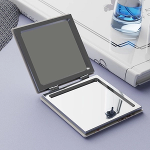 Detail of opened portable makeup mirror with a metal hinge showing a greeting card