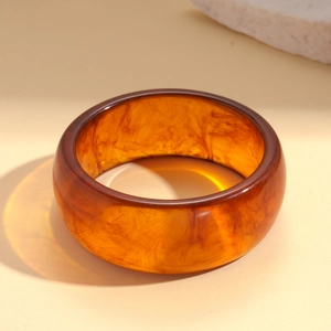 Detailed view of wide amber resin bangle with marble texture and polished finish