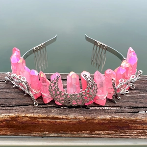 Detailed view of a pink crystal crown with metal moon and star accents on wood