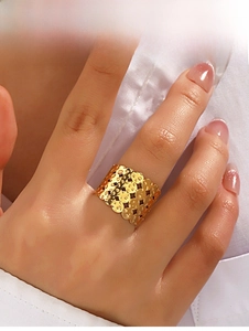 Nahaufnahme eines breiten goldfarbenen Rings mit geometrischem Hohlmuster am Finger