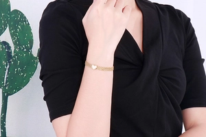 Close-up of golden multi-layer chain bracelet with white heart pendant on wrist