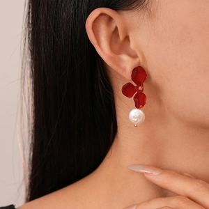 Close-up of deep red flower earrings with white freshwater pearls on a female model