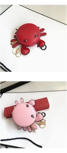 Detail of red and pink PU leather crab coin purses with gold keychains and gift box