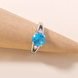 Detail of silver ring with round blue gemstone and zircon on a conical display stand