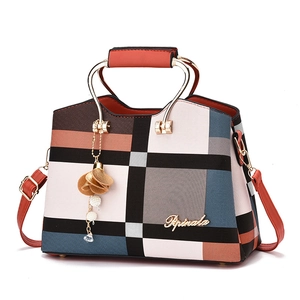 Chic color-block women's handbag with golden metal handles and elegant floral tassel