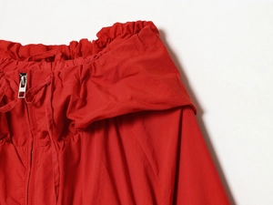 Detail of red windbreaker jacket with silver zipper, drawstring and nylon fabric texture