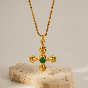 Detail view of 18K gold plated cross necklace with green stone on stone pedestal