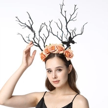 Detail of bridal headband with black branches, orange roses, and a black butterfly ornament