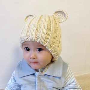 Detail of baby knitted hat featuring cute bear ears and delicate lace trim in beige
