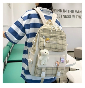 Detail of cute plaid canvas backpack with plush teddy bear charm and cartoon badges