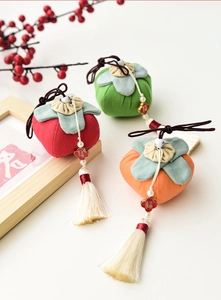 Detailed view of fabric persimmon ornaments with white tassels and gold Fu charms