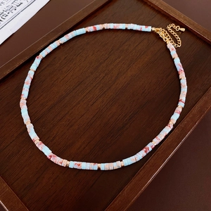 Detail view of Shoushan stone beaded necklace with gold chain on dark wood tray