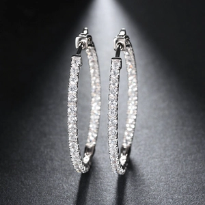 Macro detail of silver circle earrings with full AAA zircon pave setting on dark background