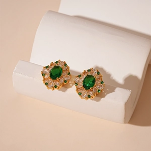 Detail of vintage gold stud earring with green oval zircon and sparkling white crystals