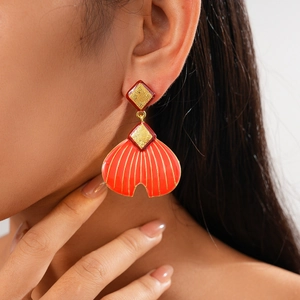 Vintage red enamel fishtail earrings with gold rhombus texture on a model