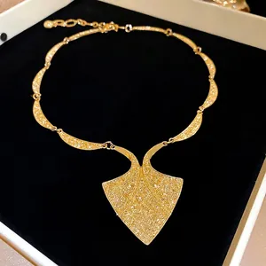 Vintage geometric gold necklace set with embossed texture on black velvet jewelry box