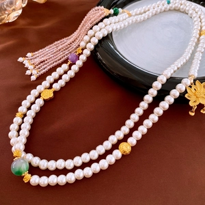 Detailed close-up of double-layer pearl necklace with golden lotus and silk tassel