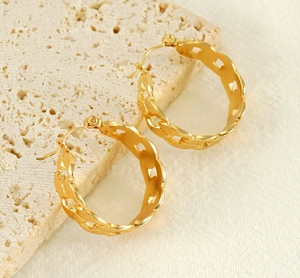 Détail de boucles d'oreilles créoles dorées avec texture de maille cubaine