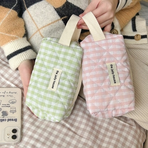 Quilted plaid makeup bags in green and pink with cotton handles and brand label