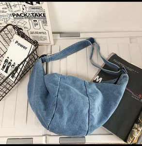 Macro shot of washed blue denim crescent bag with patchwork details and adjustable strap