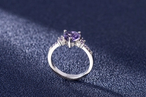Macro view of heart-shaped purple amethyst ring with zircon side stones in silver