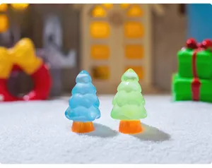 Miniature blue and green luminous Christmas trees on snow background for DIY decor