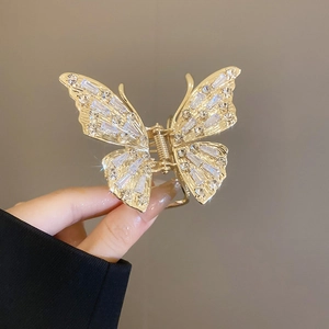 Close-up of golden metal butterfly hair claw clip with sparkling rhinestones and crystals