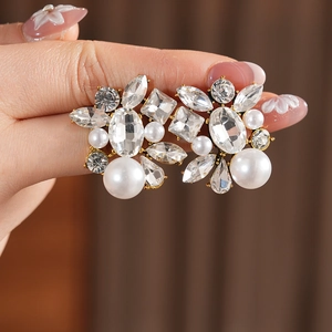 Close-up of vintage gold drop earrings with teardrop pearls and pavé crystal accents