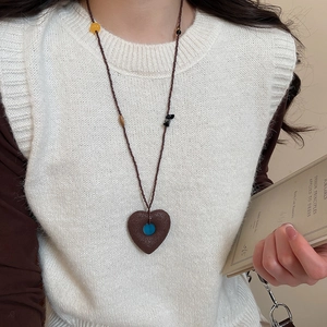 Macro detail of vintage heart pendant with blue bead and ethnic stone beaded chain