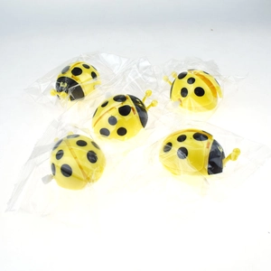 Detailed view of yellow ladybug wind-up toys in individual plastic packaging