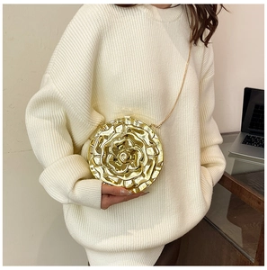 Close-up of golden rose-shaped metal evening clutch bag with detachable chain strap